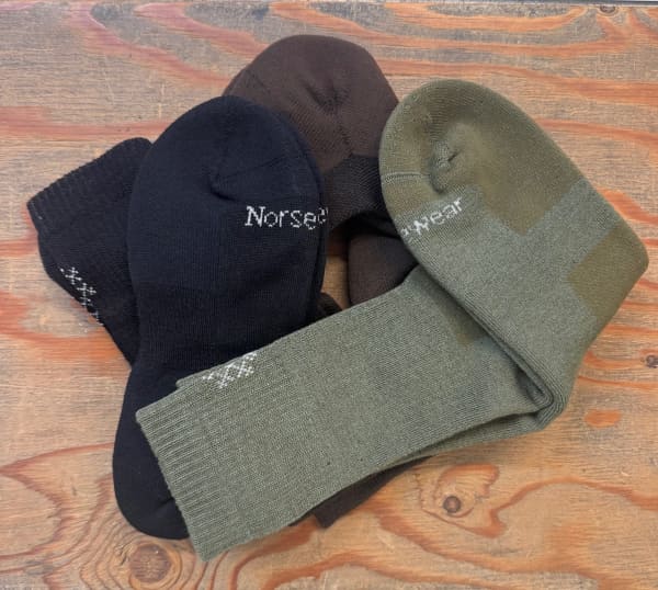 Norsewear socks in a pile on a wooden table.