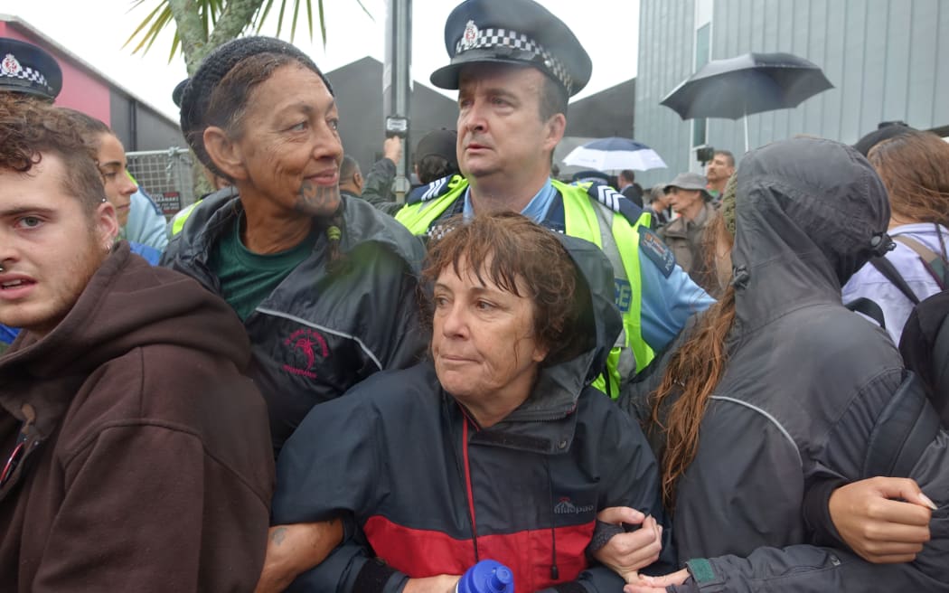 Police confront protesters outside the conference.
