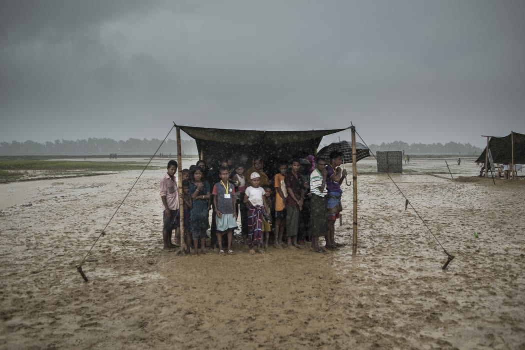 (FILES) In this file photo taken on October 6, 2017 Rohingya refugees take shelter from the rain at Nayapara refugee camp in Bangladesh's Ukhia district.