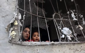 A woman and a child look out from the window of a damaged building following Israeli bombing on Rafah in the southern Gaza Strip, on November 11, 2023, as battles between Israel and the Palestinian Hamas movement continue. (Photo by SAID KHATIB / AFP)