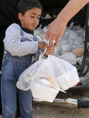 A Syrian refugee in Jordan receiving a meal distributed by World Food Programme workers.