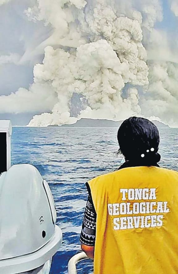 A scientist from the Tonga Geological Services watches the eruption of the volcano from a boat.
