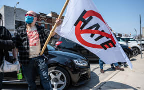 A protester listens during a speech while holding an anti-hate flag during Day of Solidarity event at the DeKalb County Court House on April 3, 2021 in Auburn, Indiana.
