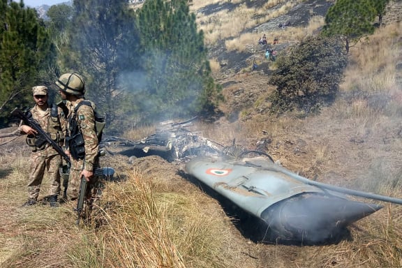 Pakistani soldiers stand next to what Pakistan says is the wreckage of an Indian fighter jet shot down in Pakistan-controlled Kashmir.