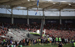 Spectators watch as firefighters work to rescue an air force parachutist whose canopy is jammed on the roof of the stadium prior to the European Rugby Champions Cup last 16 match between Toulouse and Sale at Toulouse stadium in France, 7 April, 2025.