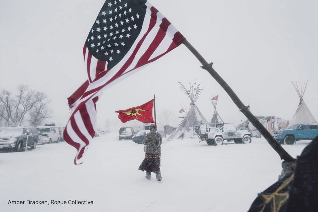 People carry an American and a Mohawk Warrior Society flag at a protest camp against the Dakota Access Pipeline.