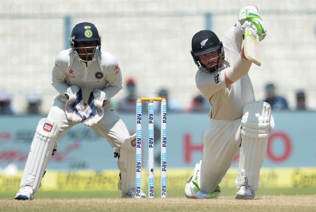 New Zealand's Martin Guptill (R) plays a shot as India's wicketkeeper Wriddhiman Saha looks on during the fourth day of the second Test match between India and New Zealand at The Eden Gardens Cricket Stadium in Kolkata on October 3, 2016. -