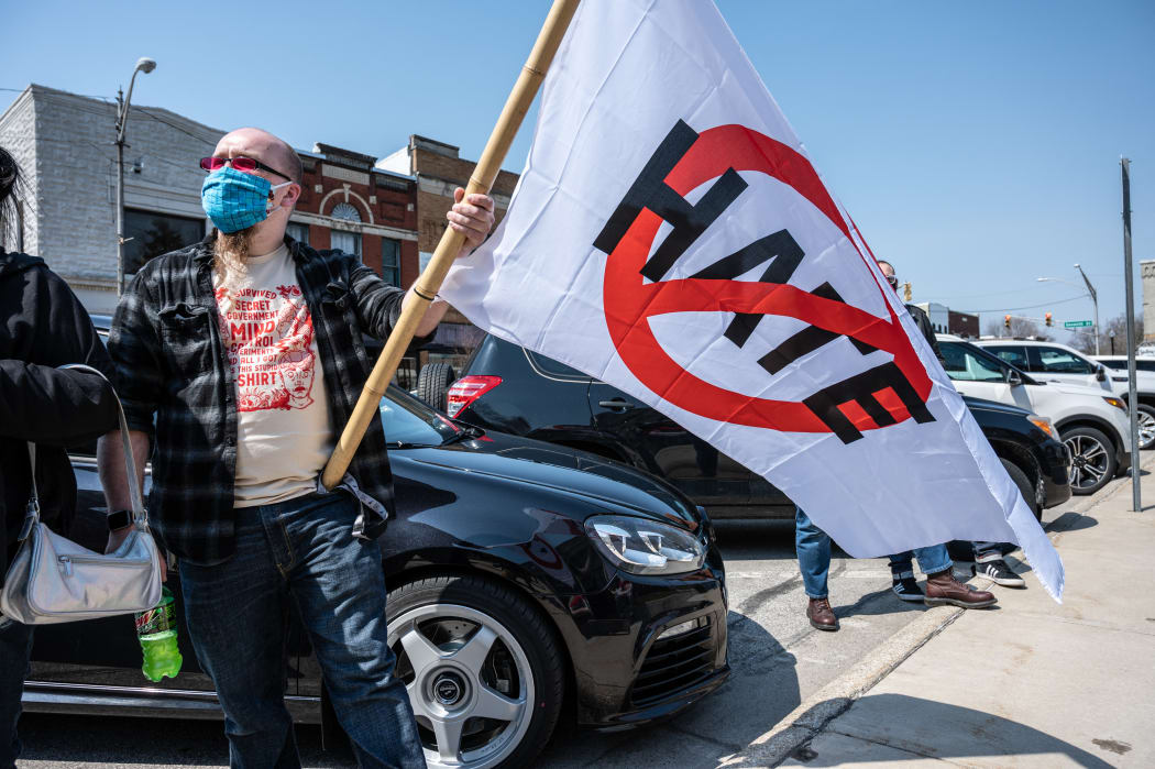 A protester listens during a speech while holding an anti-hate flag during Day of Solidarity event at the DeKalb County Court House on April 3, 2021 in Auburn, Indiana.