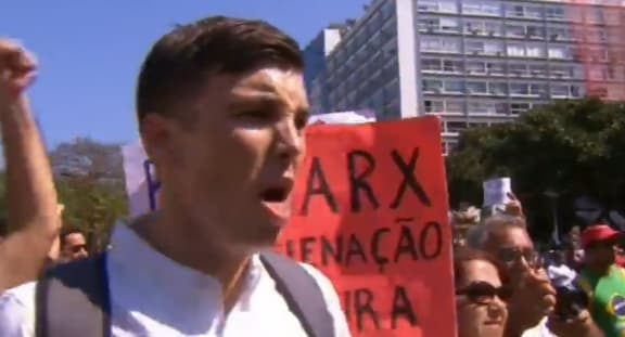 TVNZ's Jack Tame reacts to pepper spray in the air at a protest in Rio.