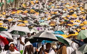 Muslim pilgrims use umbrellas to shade themselves from the sun as they arrive at the base of Mount Arafat, also known as Jabal al-Rahma or Mount of Mercy, during the annual hajj pilgrimage on June 15, 2024. Friends and family searched for missing hajj pilgrims on June 19 as the death toll at the annual rituals, which were carried out in scorching heat, surged past 900. (Photo by Fadel SENNA / AFP)