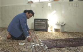 Abdul Aziz places markers designed to maintain distance between worshippers at Linwood mosque.