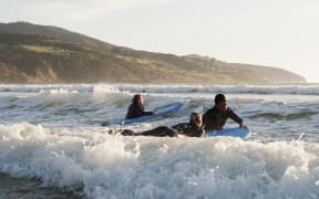 Surfing at Raglan Beach, Waikato.