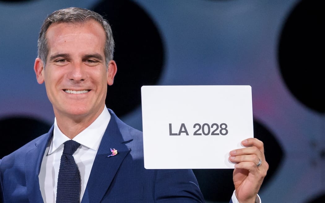 Los Angeles Mayor Eric Garcetti gets emotional  as he holds a card bearing the name of LA 2028 after the vote during the 131st International Olympic Committee (IOC) session in Lima on September 13, 2017. The ICO meeting in Lima confirmed Paris and Los Angeles as hosts for the 2024 and 2028 Olympics, crowning two cities at the same time in a historic first for the embattled sports body. (Photo by Fabrice COFFRINI / AFP)