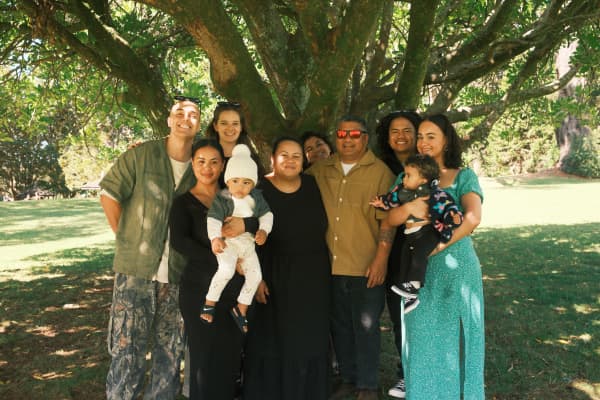 Tōtara Hospice community networking lead Marleen Tuigamala stands with her family members under a tree.
