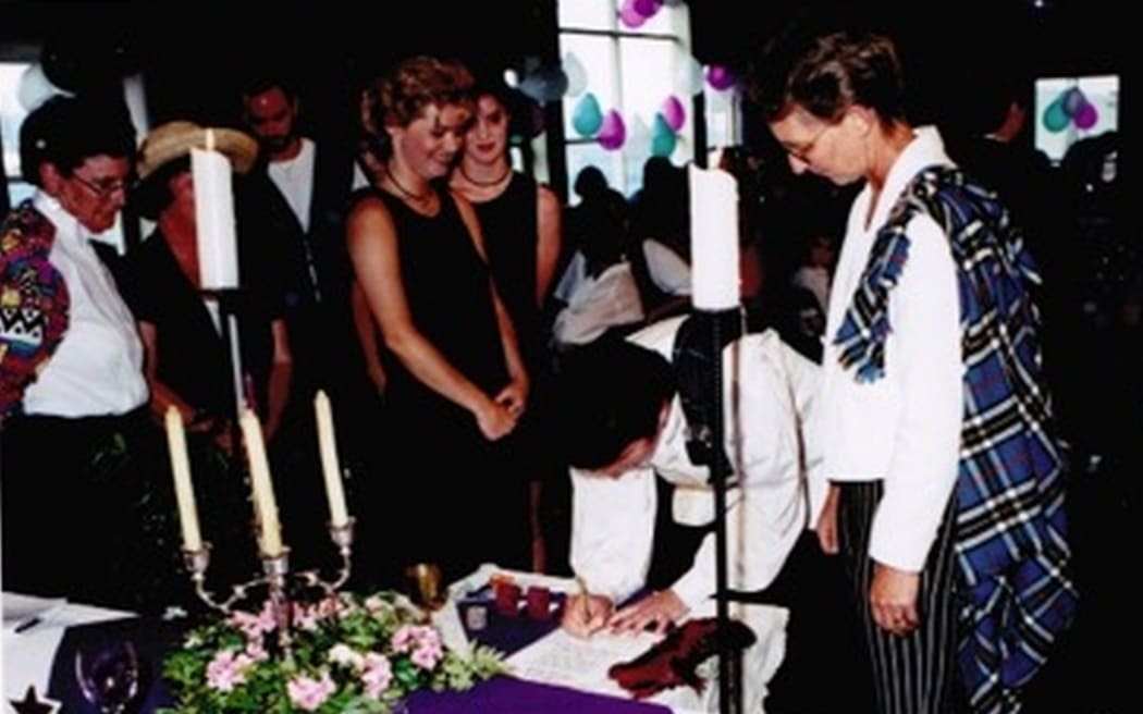 An image of the couple signing the marriage register.