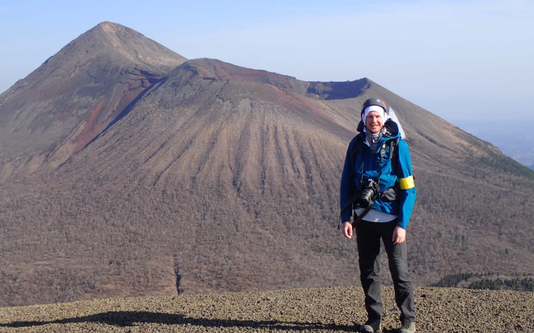 Christ Conway is wearing tramping gear and standing in front of a Japanese volcano.