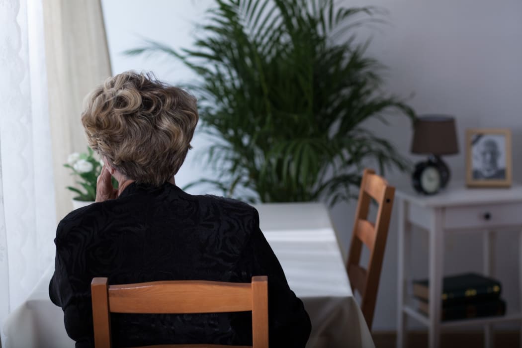 Depressed elderly widow sitting alone at home
