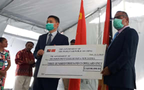 China's Ambassador in Papua New Guinea, Xue Bing, presents a cheque to PNG's Foreign Minister Patrick Pruaitch at Port Moresby General Hospital.
