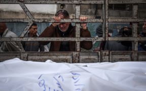A man mourns as the shrouded bodies of loved ones killed during Israeli bombardment arrive at Al-Najar hospital in Rafah on the southern Gaza Strip on December 29, 2023, amid continuing battles between Israel and the Palestinian militant group Hamas.