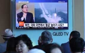 People watch a television news programme, showing file footage of a North Korean missile launch, at a railway station in Seoul on May 14, 2017.