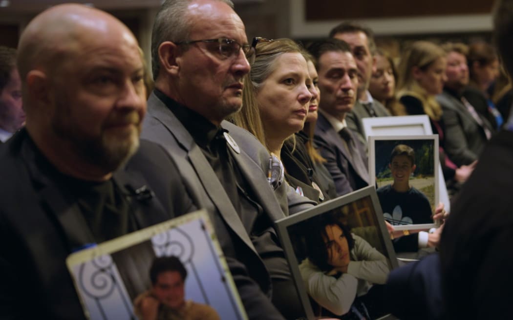 Photo taken down a row of parents sitting with photographs of their children who have died