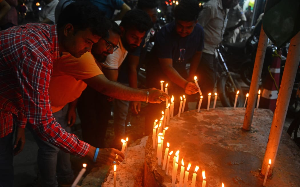 People light candles as they take part in a prayer ceremony in Siliguri on June 12, 2025, for the victims of the airplane crash in India's Ahmedabad city. Thick black plumes of acrid smoke towered high above India's Ahmedabad airport on June 12 after a London-bound passenger jet with 242 people aboard crashed shortly after takeoff. (Photo by Diptendu DUTTA / AFP)