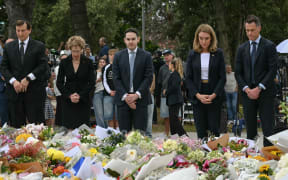 New South Wales Premier Chris Minns (R) and other dignitaries lay flowers as a tribute at the Bondi Pavillion in memory of the victims of a shooting at Bondi Beach, in Sydney on December 15, 2025. A father and son opened fire on a Jewish festival at Australia's Bondi Beach in a shooting spree that killed 15 people, including a child, authorities said on December 15, denouncing the attack as antisemitic "terrorism". (Photo by Saeed KHAN / AFP)