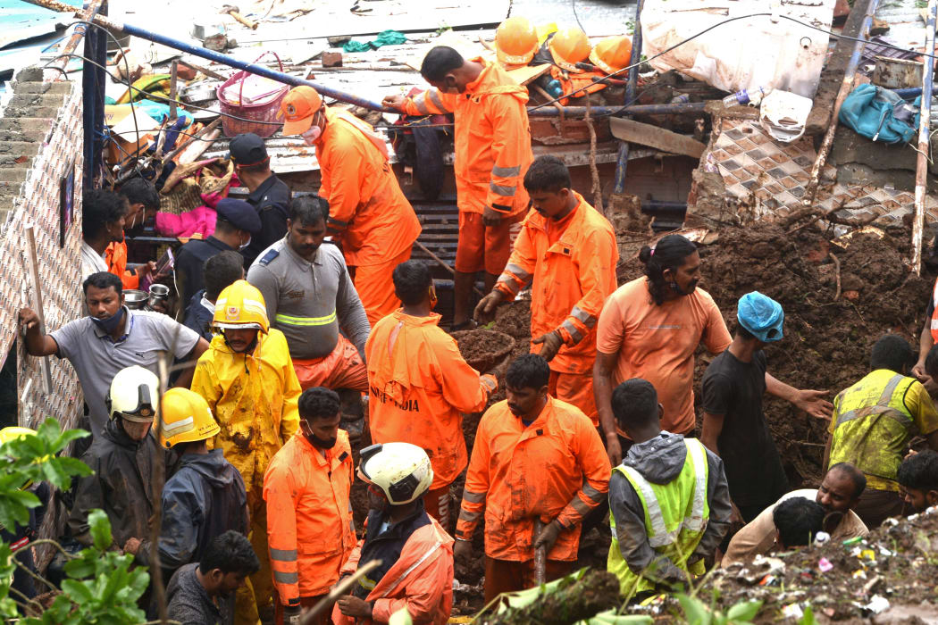 Rescue team personnel inspect the site of the landslide in a slum area where 25 people were killed after several homes were crushed by a collapsed wall and a landslide triggered by heavy monsoon rains in Mumbai.