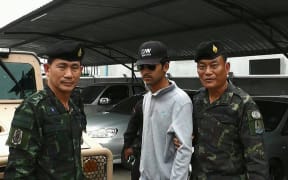 Thai police escort a suspect (centre) arrested on the Thai side of the Cambodian border on 1 September in connection with the bomb attack in Bangkok on 17 August.