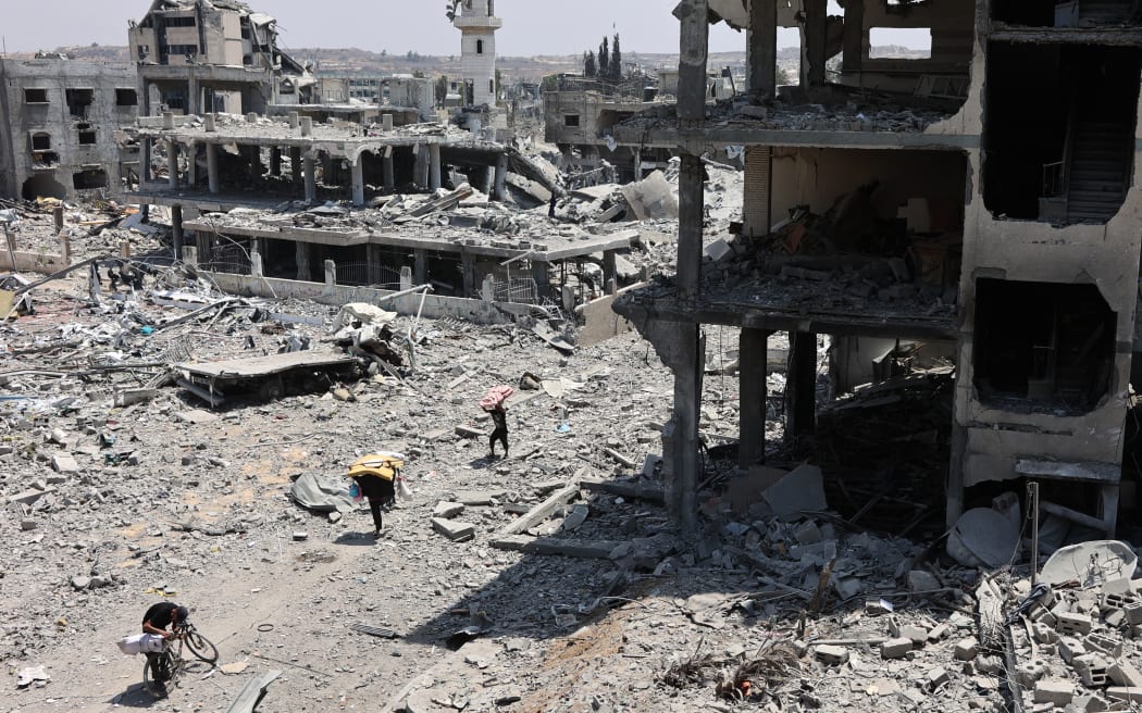 Palestinians transport salvaged items past destroyed buildings in the al-Tuffah neighbourhood of Gaza City on August 14, 2025, following more than 22 months of war between Israel and the Palestinian militant group Hamas. The Israeli military said on August 13, that it had approved the framework for a new offensive in the Gaza Strip, as Hamas condemned what it called "aggressive" Israeli ground incursions in Gaza City. The approved plan for the expanded offensive comes days after Israel's security cabinet called for the capture of the Palestinian territory's largest city following 22 months of war that have created dire humanitarian conditions. (Photo by Omar AL-QATTAA / AFP)