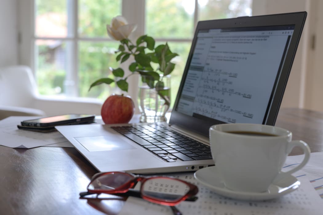 laptop with mathematical formulas on the screen, coffee cup, glasses and a fresh apple on the desk of a student, programmer or a freelancer small business home office.