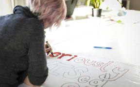 Principal Traci Liddall at South Wellington Intermediate School prepares a banner for the teachers strike.