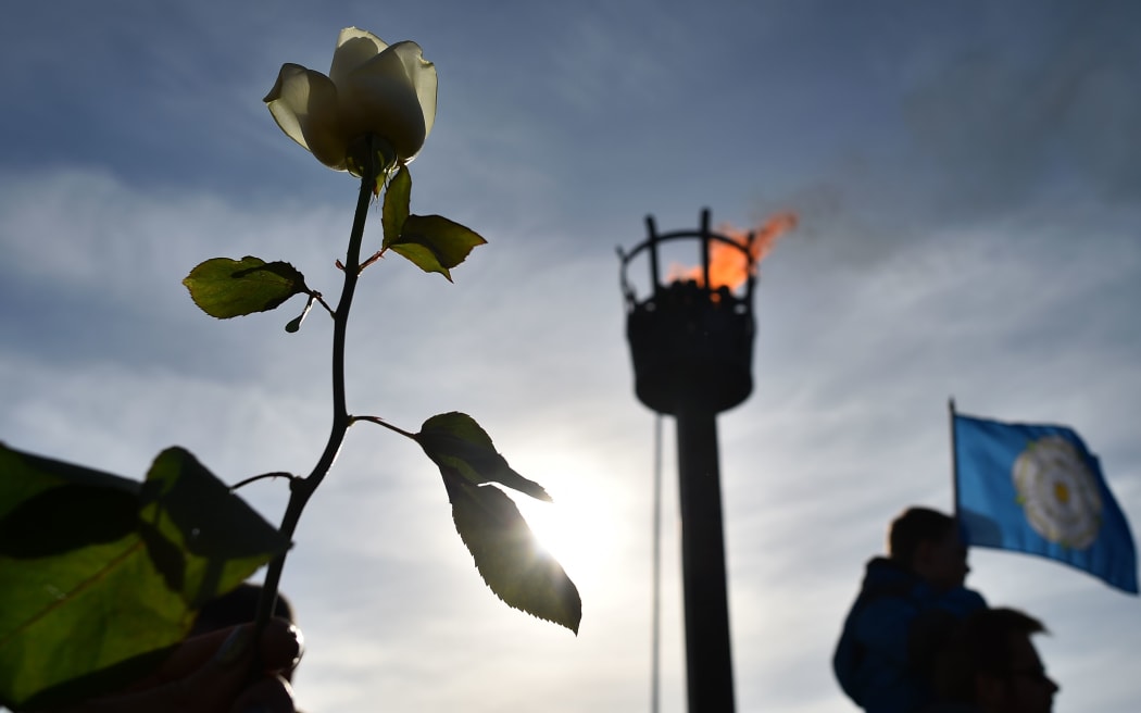 A member of the public holds a white rose in front of the battlefield beacon following a ceremony for King Richard III