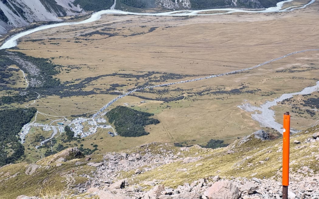 A photo taken from the ridge above Sealy Tarns on the way to Mueller Hut shows traffic backed up on the road to a carpark in Aoraki National Park.