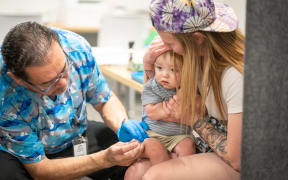LUBBOCK, TEXAS - MARCH 01: One year-old River Jacobs is held by his mother, Caitlin Fuller, while he receives an MMR vaccine from Raynard Covarrubio, at a vaccine clinic put on by Lubbock Public Health Department on March 1, 2025 in Lubbock, Texas. Cases of Measles are on the rise in West Texas as over 150 confirmed case have been seen with one confirmed death.  Jan Sonnenmair/Getty Images/AFP (Photo by Jan Sonnenmair / GETTY IMAGES NORTH AMERICA / Getty Images via AFP)