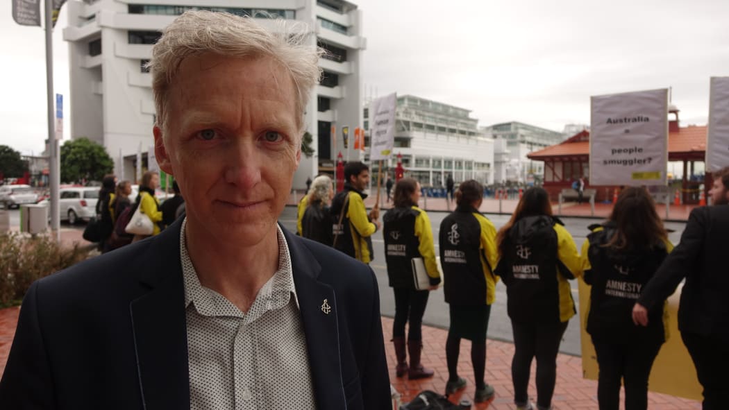 Grant Baildon stands in front of Amnesty International protesters in Auckland.