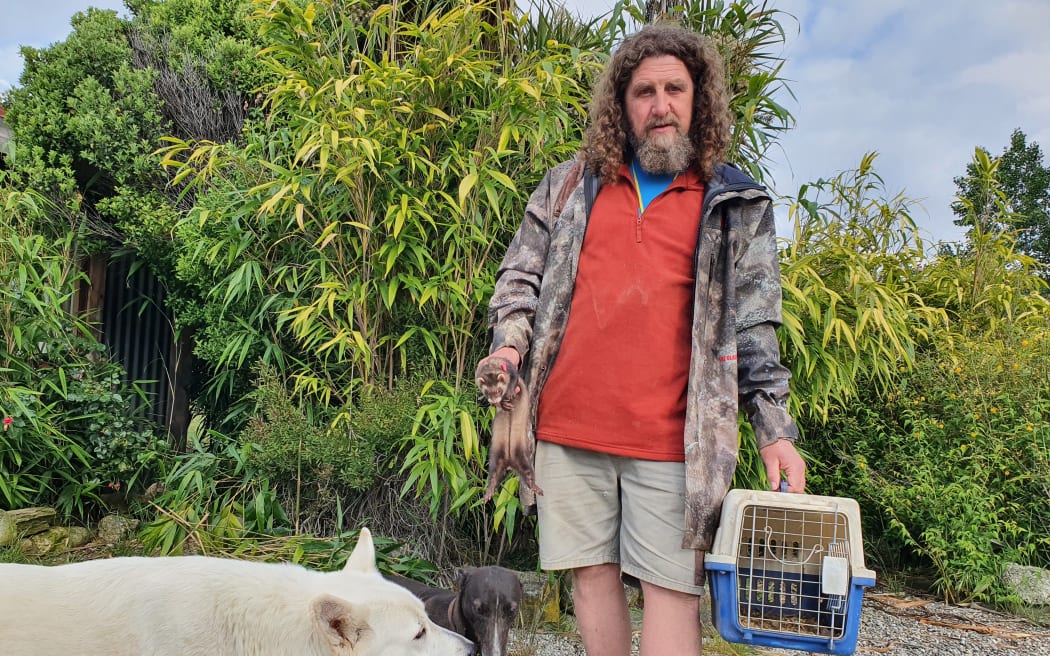 Billy Barton with one of his white shepherds, Evelyn, the rabbit dog, and Brownie, the ferret.