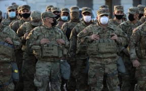 WASHINGTON, DC - JANUARY 14: National Guard troops pose for photographers on the East Front of the U.S. Capitol the day after the House of Representatives voted to impeach President Donald Trump for the second time January 14, 2021 in Washington, DC.