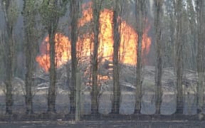 Flames leap to a rubbish pile and set it alight.