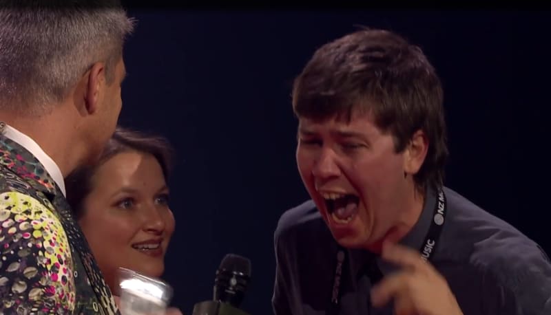 Callum Devlin (right) of Filmmaking duo Sports Team shouts into a microphone held by Aotearoa Music Award host Jesse Mulligan, with Annabel Kean (centre).