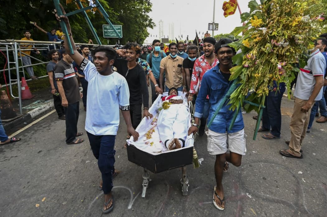 University students push a coffin with a demonstrator dressed as Sri Lanka's Prime Minister Mahinda Rajapaksa during a demonstration demanding his resignation.