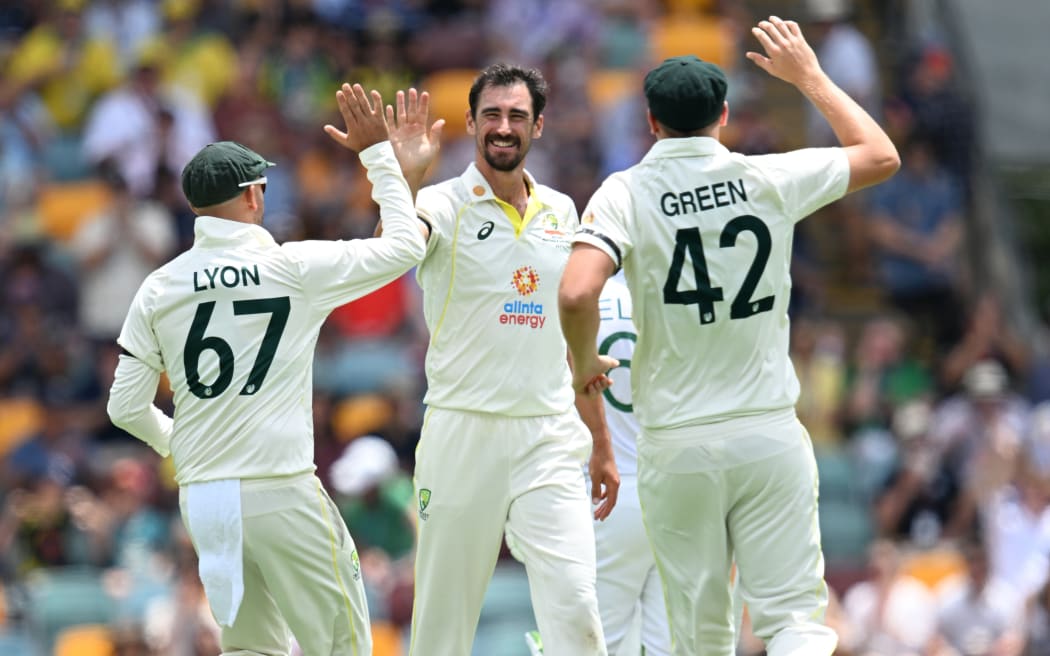 Mitchell Starc (centre) of Australia celebrates with team mates Nathan Lyon (left) and Cameron Green (right) after getting the wicket of Dean Elgar of South Africa during day one of the First Test Between Australia and South Africa at the Gabba in Brisbane, Saturday, December 17, 2022. (AAP Image/Darren England/ www.photosport.nz