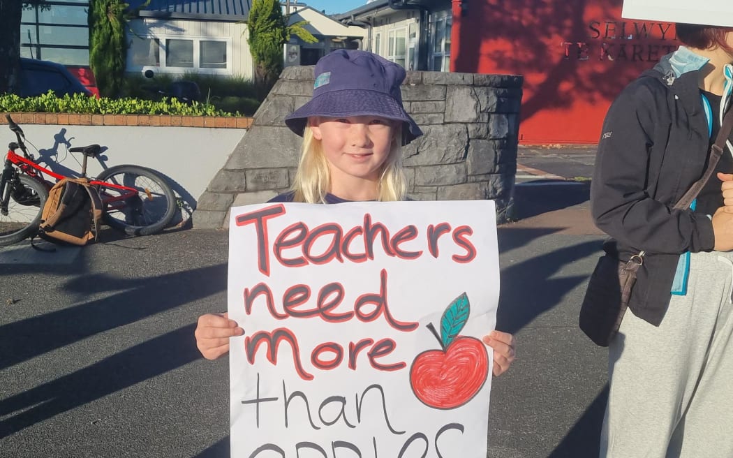 A child holds a placard in support of striking teachers outside Selwyn College in Auckland on Wednesday, 29 March.