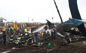 Nepali rescue workers gather around the debris from the deadly plane crash.