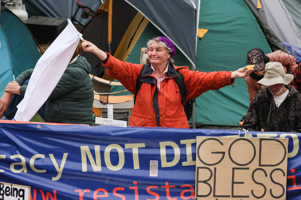 A protestor holds up a white flag and, for some reason a portion of rock melon.