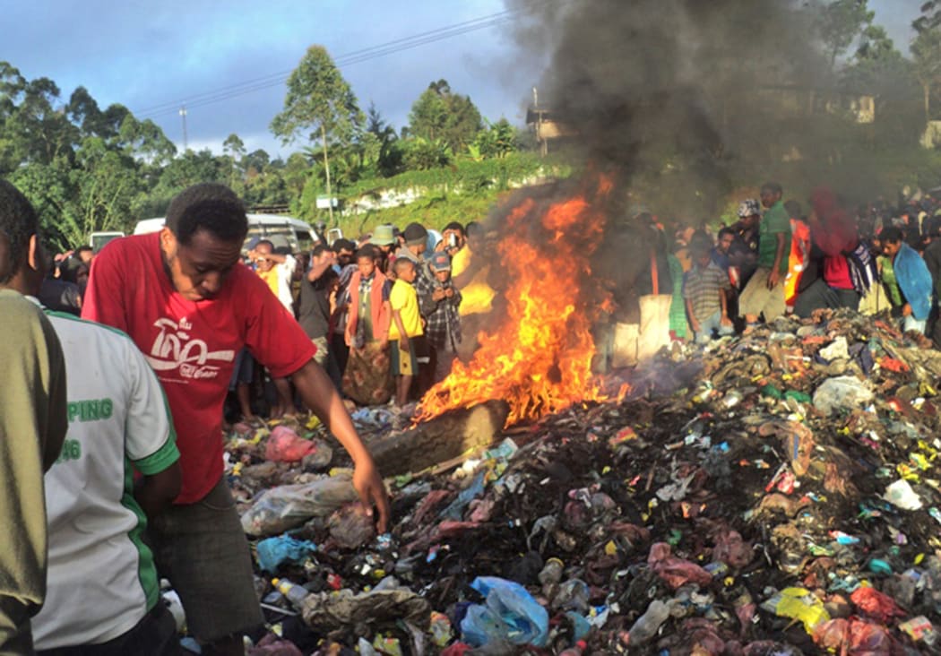 A photo taken on February 6, 2013 shows a crowd watching as a young mother accused of sorcery, is stripped naked, reportedly tortured with a branding iron, tied up, splashed with fuel and set alight