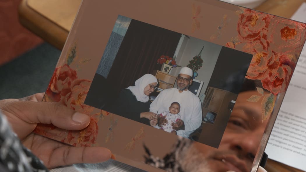 Farid Ahmed holding an old photo of him with his wife Husna, who died in the 15 March shootings, and his daughter.