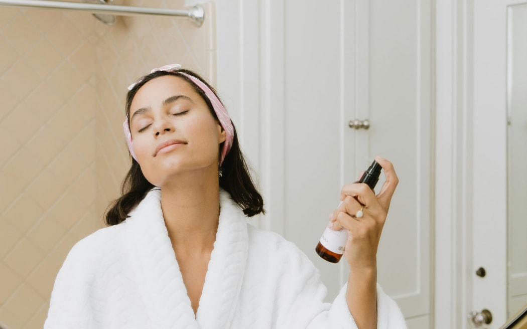 Woman spraying herself in bathroom