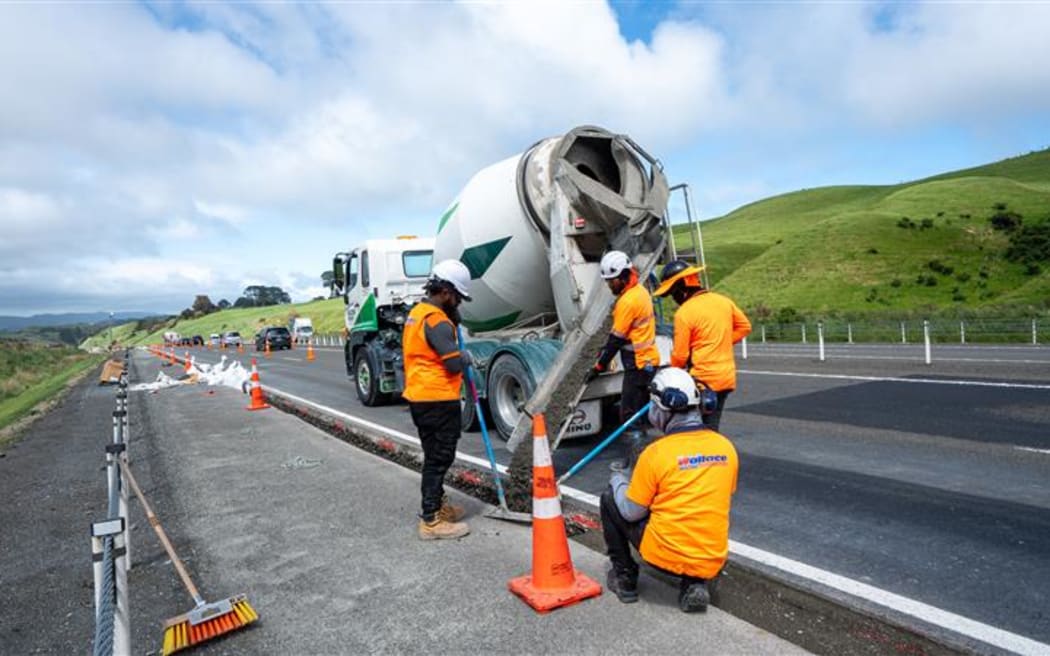 Contractors backfilling concrete next to the southbound lane after drainage has been installed.