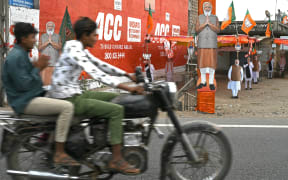 Motorists ride past a cut-out of India's Prime Minister Narendra Modi installed at the venue of Bharatiya Janata Party (BJP) election campaign in Rajkot district of Gujarat state on May 5, 2024, ahead of the third phase of voting of the country's general election. (Photo by Indranil Mukherjee / AFP)